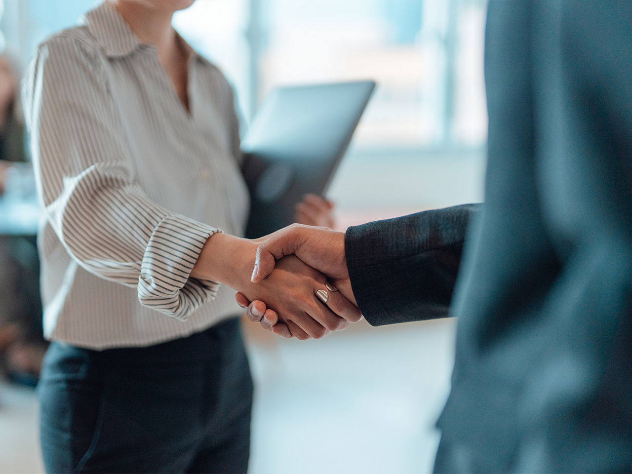 Two people in an office setting exchange a handshake  