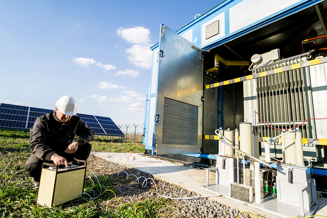 A technician maintains a battery energy storage system.