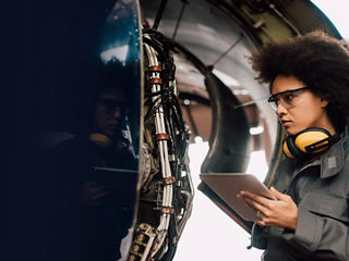 Female engineer assessing aircraft engine