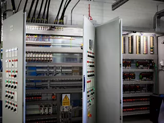 Open industrial control panels with DIN rail-mounted terminal blocks, wiring and electrical components.