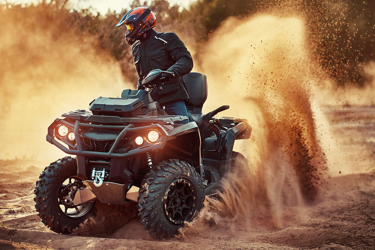 Teen riding ATV in sand dunes making a turn in the sand