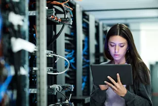A network engineer holding a tablet and working in a data center. 
