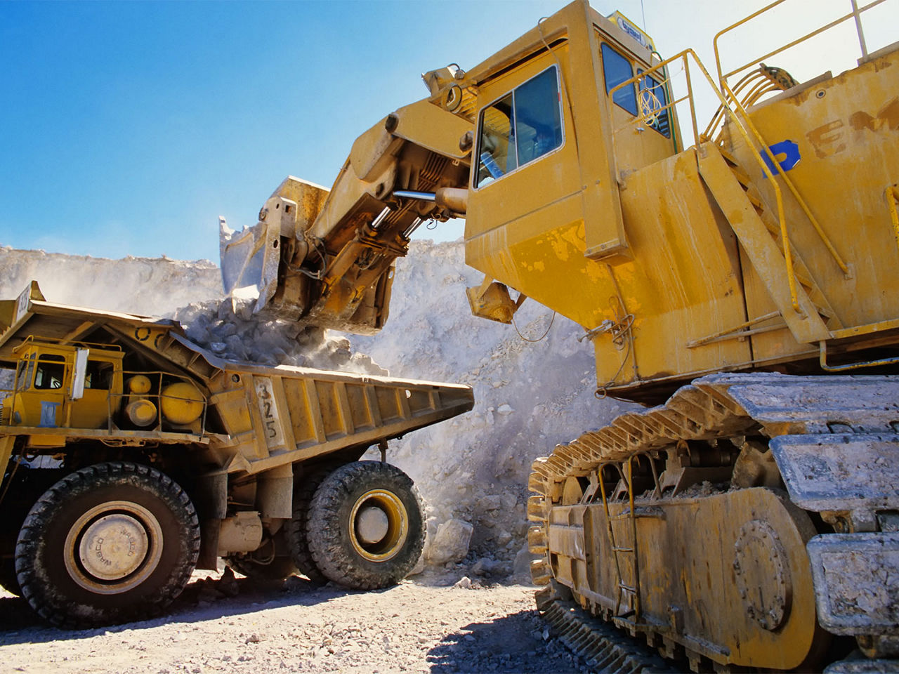 Excavator and dump truck utilizing heavy equipment connectivity at a mining site.