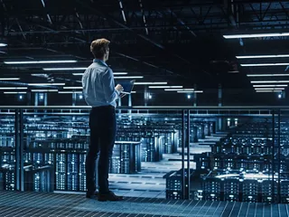 Hyperscale data center design engineer looks over racks of servers. 