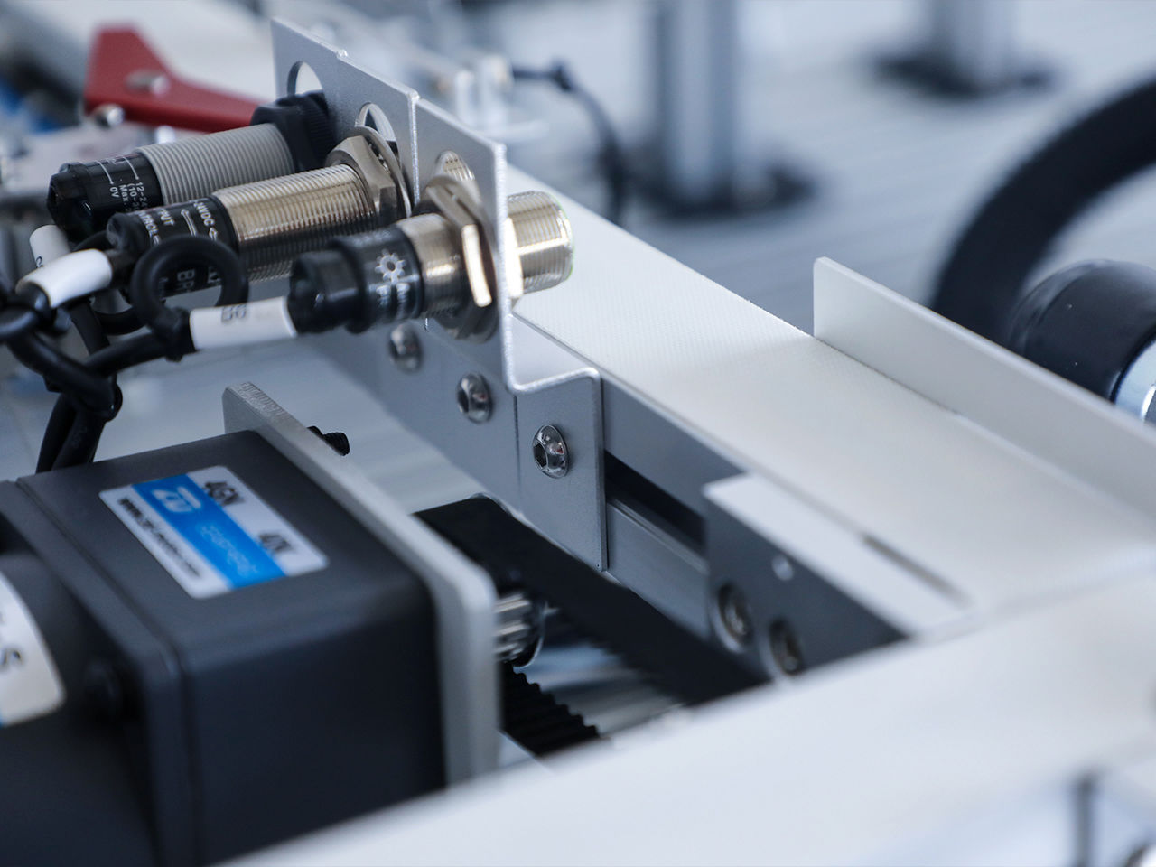 An industrial automation conveyor system featuring integrated proximity sensors and modular machine network cabling.