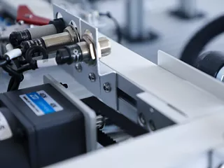 An industrial automation conveyor system featuring integrated proximity sensors and modular machine network cabling.