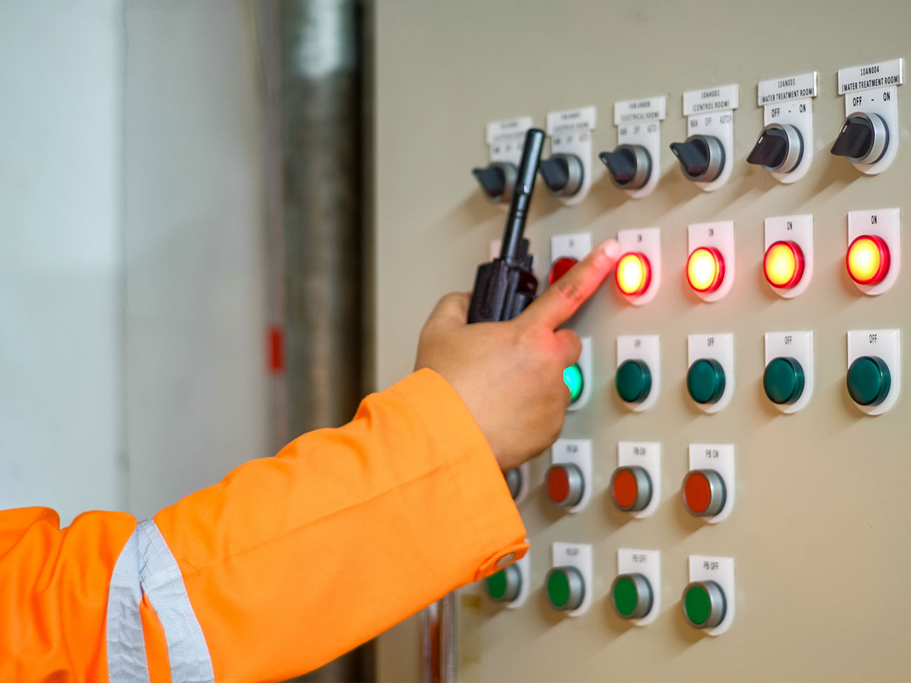 Industrial operator using a control panel with status lights to monitor equipment and facilitate diagnostic maintenance.