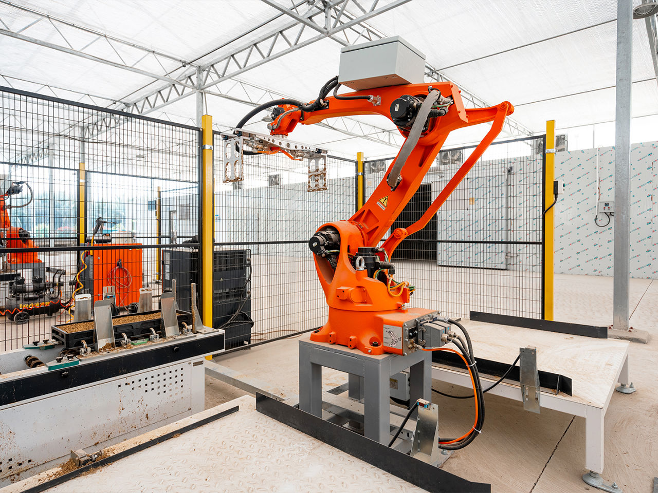 Industrial robotic arm operating in an automated manufacturing facility with compact cable routing along its structural frame.