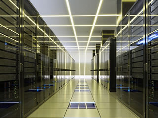 A futuristic data center interior featuring rows of server racks glowing with blue and yellow LED lights, representing high-speed data processing and on-ASIC integration in a hyperscale environment.