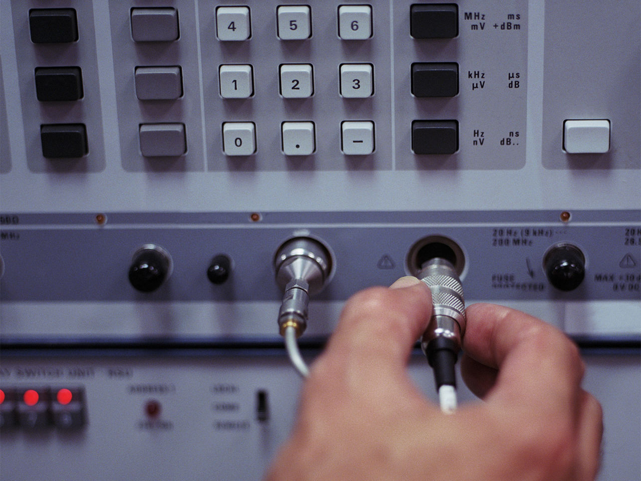 Technician connecting cable to RF test and measurement equipment.