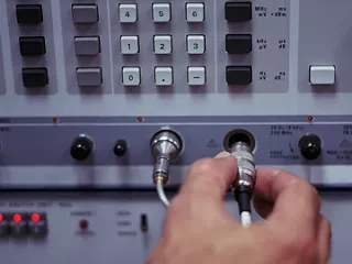 Technician connecting cable to RF test and measurement equipment.