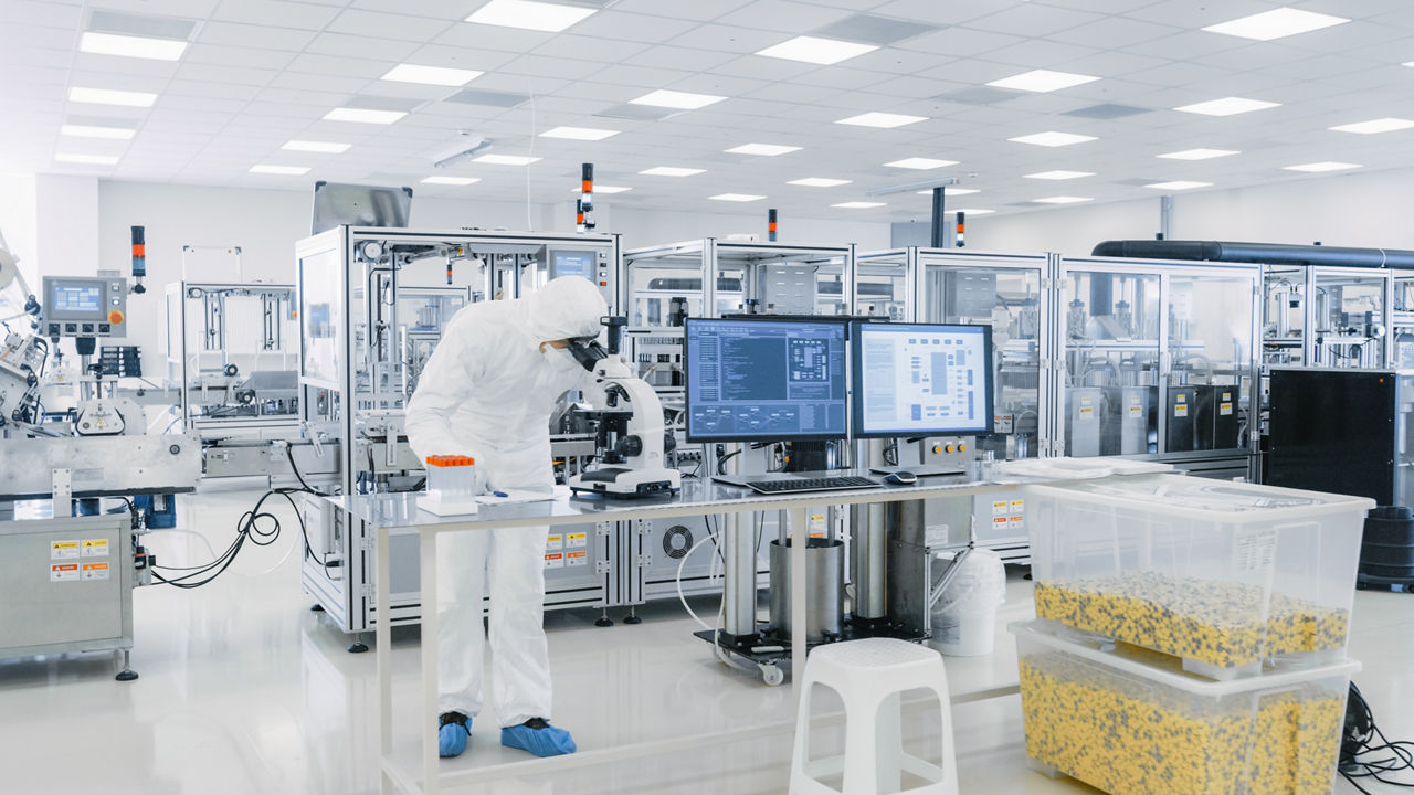 Shot of Sterile Pharmaceutical Manufacturing Laboratory where Scientists in Protective Coverall's Do Research, Quality Control and Work on the Discovery of new Medicine.