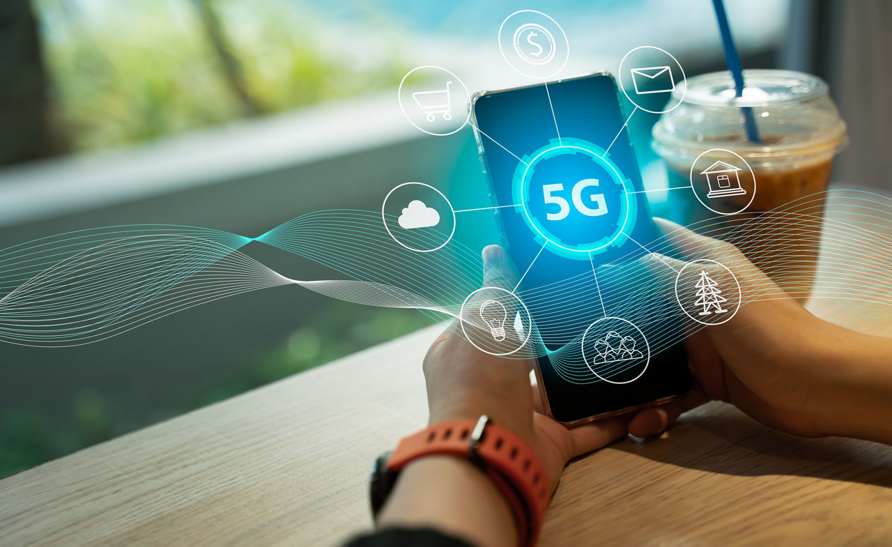 Close up of female hand holding a phone with a 5G hologram in coffee shop. 5G network wireless systems.The concept of 5G network, high-speed mobile Internet, new generation networks.