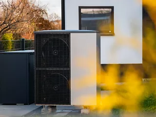 Outdoor residential HVAC unit next to a modern house. 