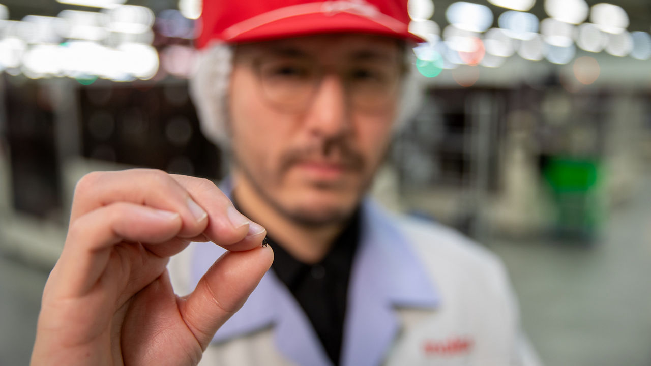 Engineer holding Quad-Row Connector between thumb and index finger. 
