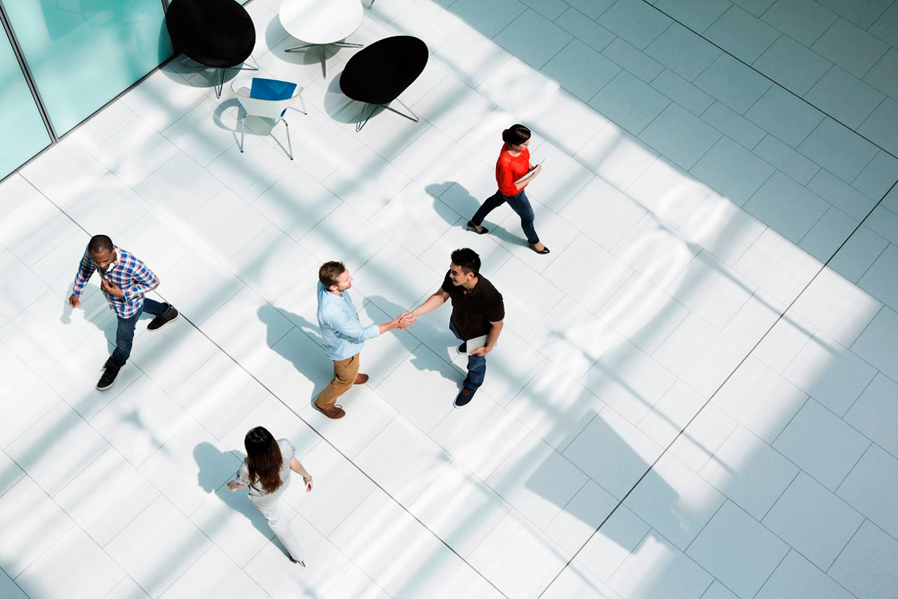 People shaking hands in the center of a modern office.    