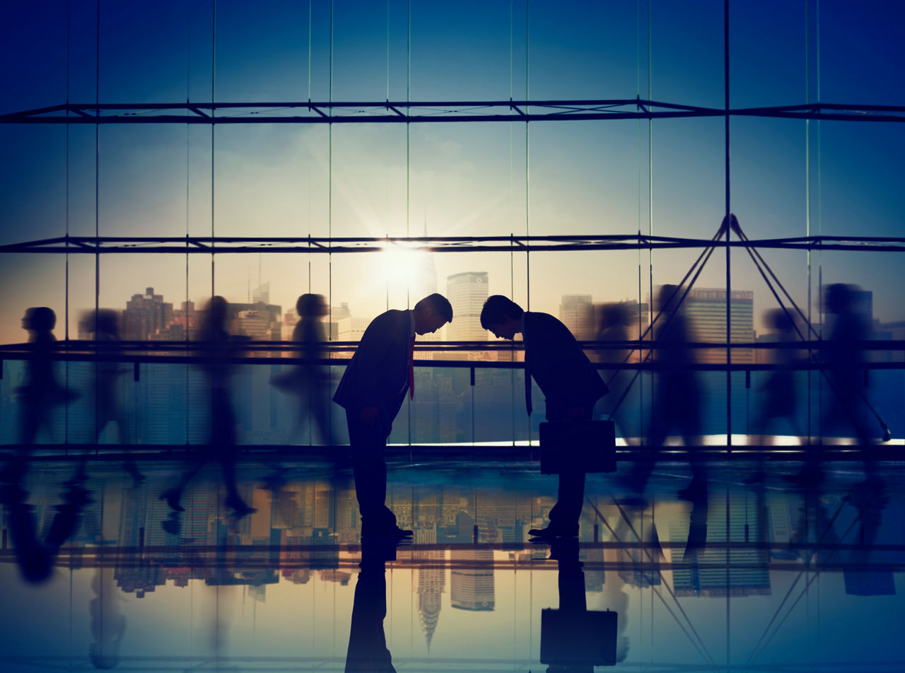 近代的なオフィスの中央で握手をする人々。