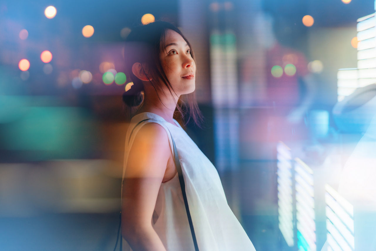 Young Asian businesswoman looking at financial data, standing in front of digital display. Futuristic concepts. Future technology. Cryptocurrency investment.