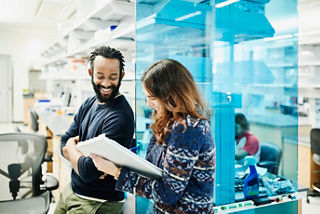 Smiling scientists in discussion while filling out paperwork in research lab