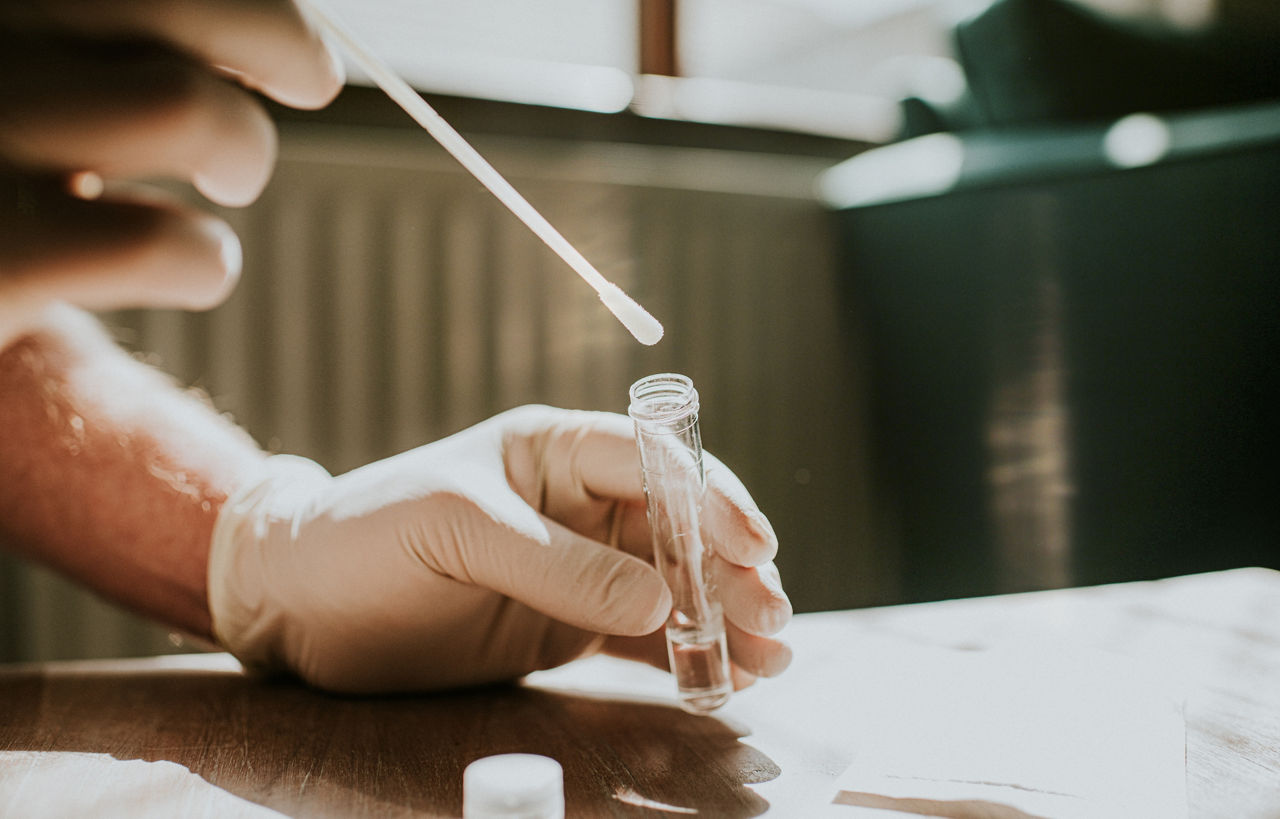 Technician putting a swab into a test tube.